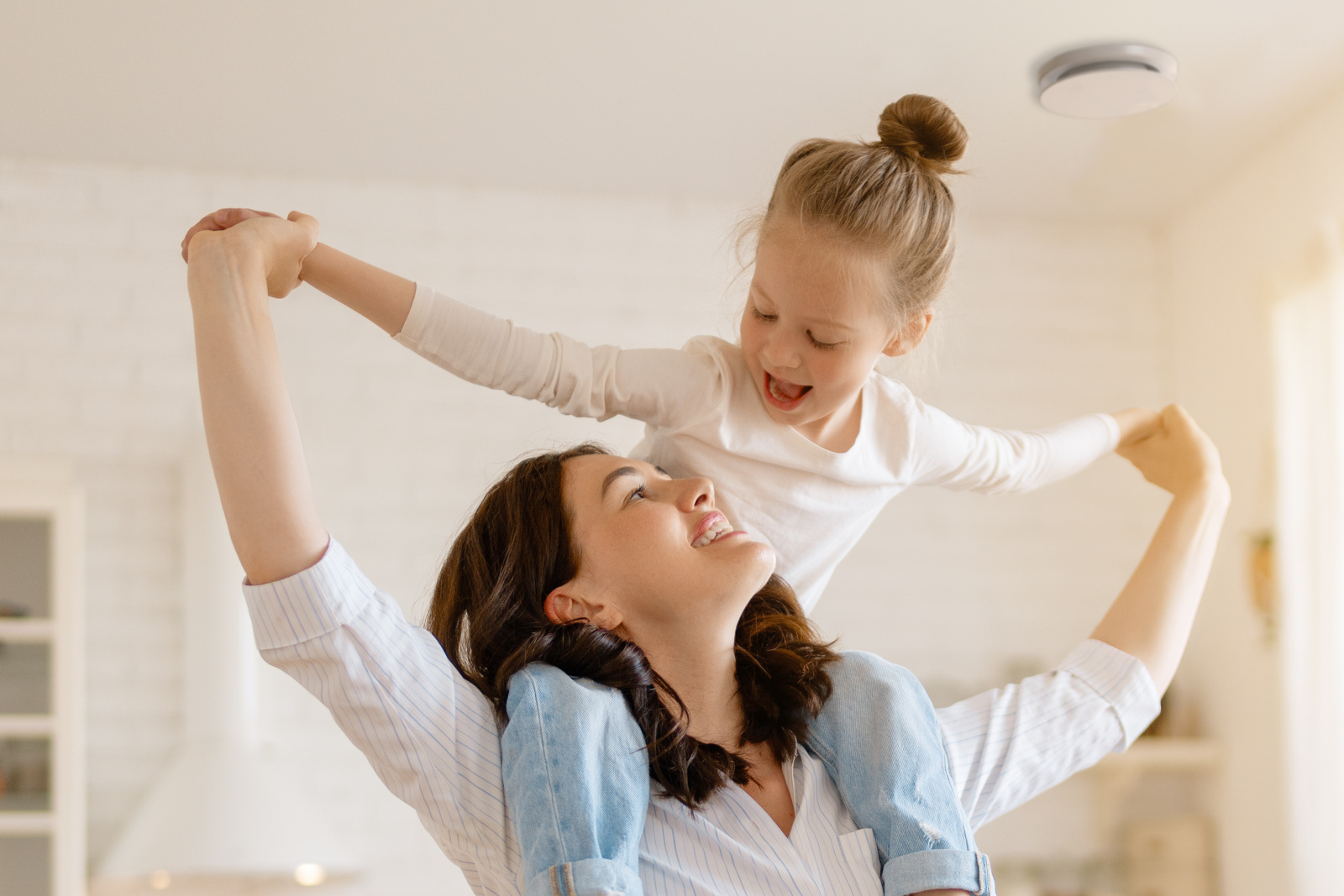 Zehnder_CSY_ComfoValveLuna_Milieu_KitchenMotherDaughter Comfo Valve Luna, mother with daughter on her shoulders, kitchen, laughing, happy, base Image AdobeStock_451026481,