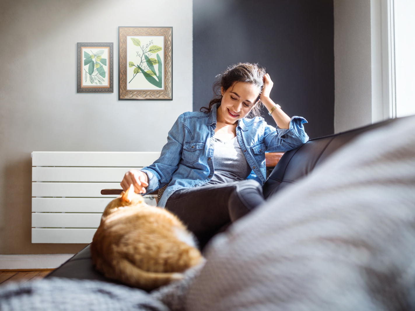 Beautiful young woman relaxing on sofa with her cat in living room.