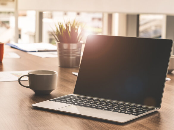 Laptop computer with opened lid on table in meeting room of office workspace.